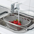 Large stainless steel colander (36x9 cm) resting over a sink basin, draining water from fresh strawberries and raspberries.